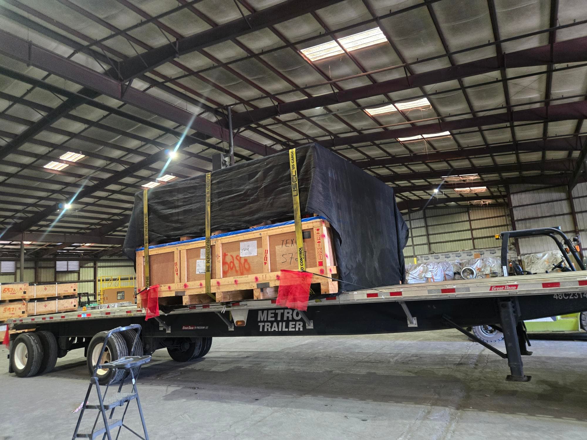 Crated freight staged on a flatbed trailer inside an IWS warehouse